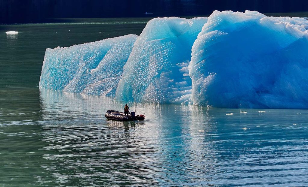 Hombre en una zodiac comprobando el deshielo de un iceberg gigante en un fiordo de Alaska. (twenty20photos)