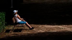 Una mujer toma el sol en un banco del Parque de El Retiro.