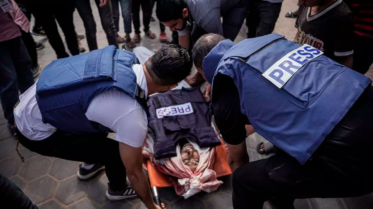 Colegas del periodista Salem Abu Tayour lo llevan en medio del patio del Hospital de los Mártires de Al-Aqsa en Deir al-Balah en Gaza